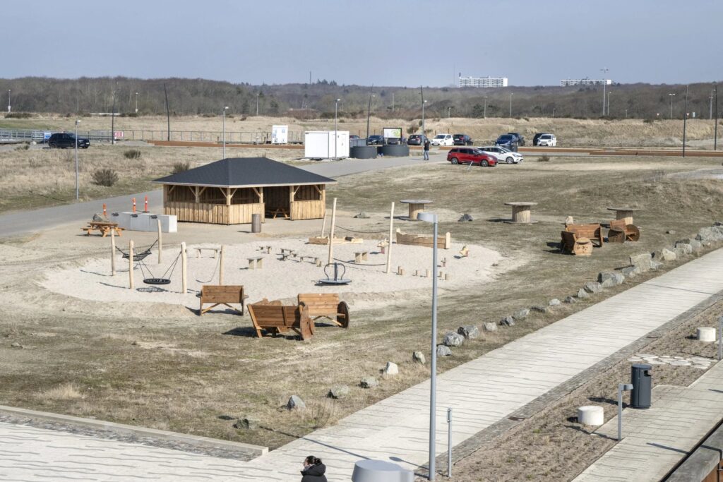 Overblik over aktivitetsområdet ved Esbjerg Strand med langhus, gynge, karrusel og sandleg