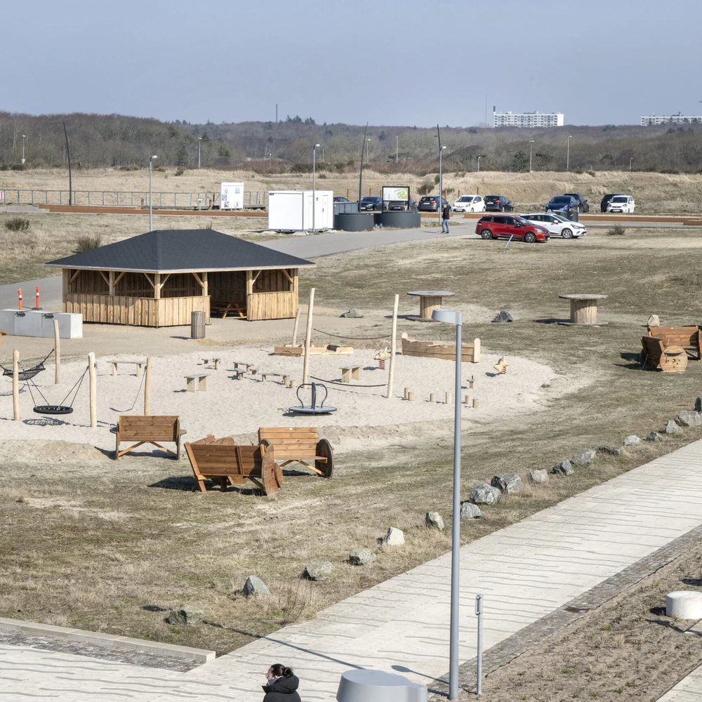 Overblik over aktivitetsområdet ved Esbjerg Strand med langhus, gynge, karrusel og sandleg