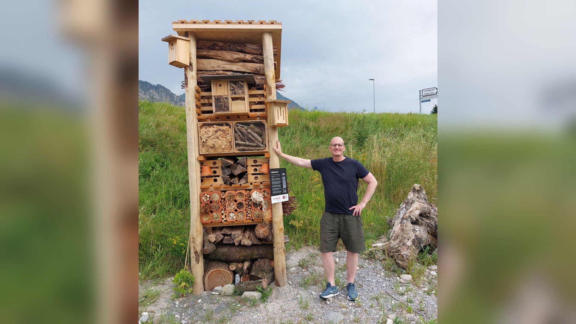 Opført insekthotel i robinie, lærk og eg med en voksen person stående ved siden af, der viser konstruktionens højde på 350 cm