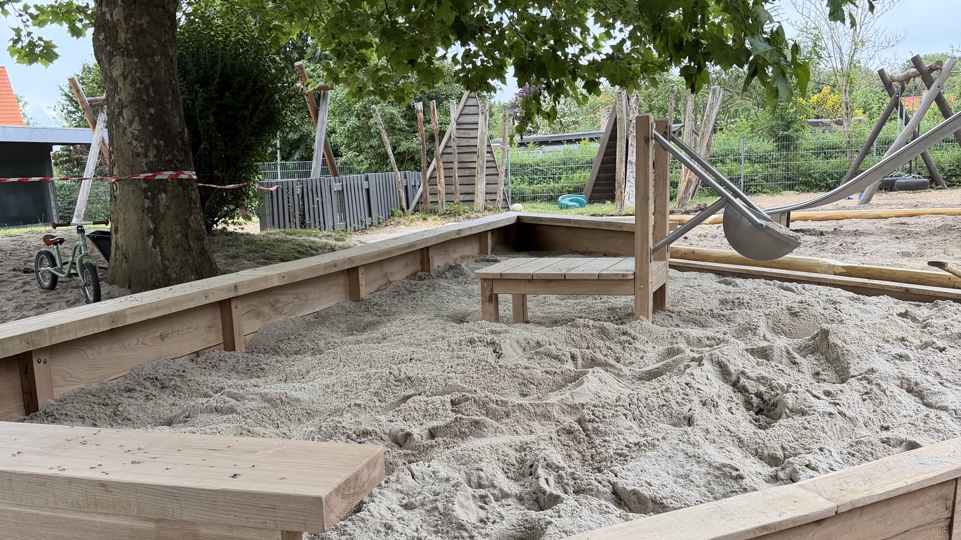 Sandkasse i lufttørret kerneeg med integrerede siddebænke og sandbord med vippeskål i rustfrit stål i Risvangens Børnehus